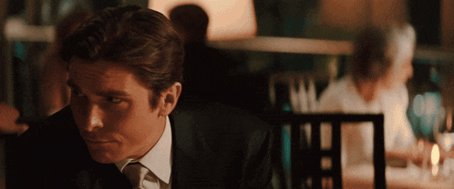 a man in a suit and tie is sitting at a table in a restaurant