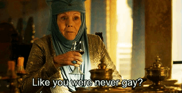 a woman is sitting at a table holding a glass of wine and asking if she were never gay