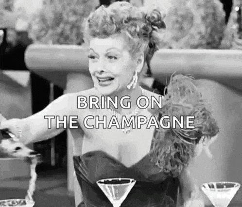a woman in a dress is sitting at a table with two martini glasses and a glass of champagne .