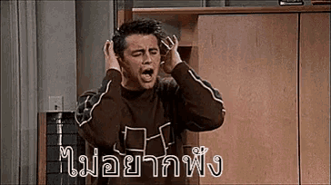 a man is covering his ears with his hands and screaming in a room .