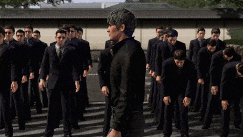 a man in a black shirt is standing in front of a group of men in suits