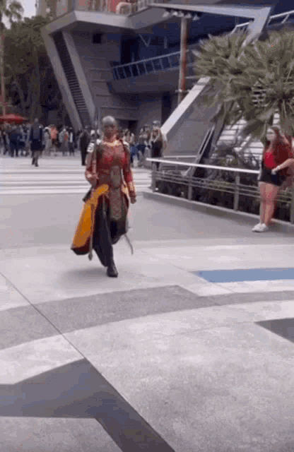a woman in a costume is walking down a sidewalk in front of a building