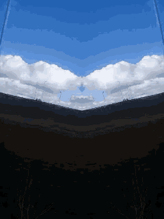 a blue sky with white clouds and a dark landscape