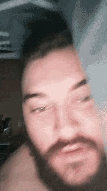 a man with a beard looks at the camera