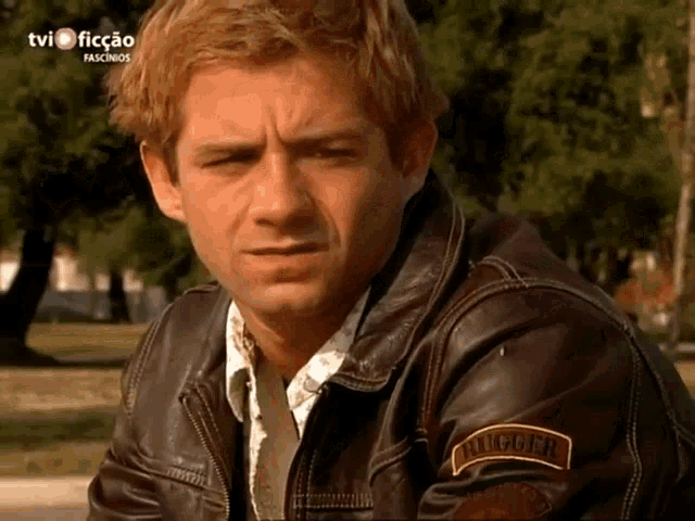 a man wearing a brown leather jacket has a patch on his sleeve that says rugged