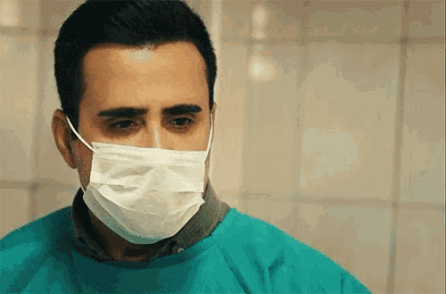 a man wearing a surgical mask and a green scrub