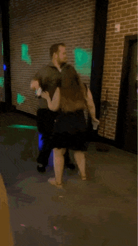 a man and a woman are dancing on the sidewalk in front of a building .