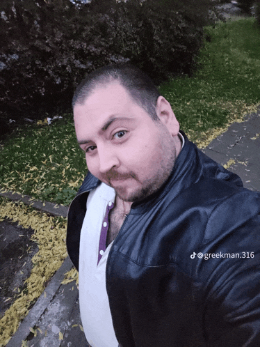 a man wearing a black leather jacket is taking a selfie with the hashtag @ greekman 316