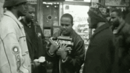a group of men standing around a man holding a gun in a black and white photo .