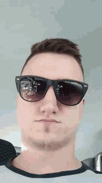 a man wearing sunglasses has a reflection of himself in the lenses