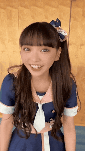 a girl wearing a blue dress and tie is smiling for the camera