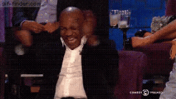 mike tyson is sitting in a chair with his hands on his head and laughing .