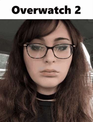 a woman wearing glasses is sitting in a car with the words overwatch 2 on the bottom