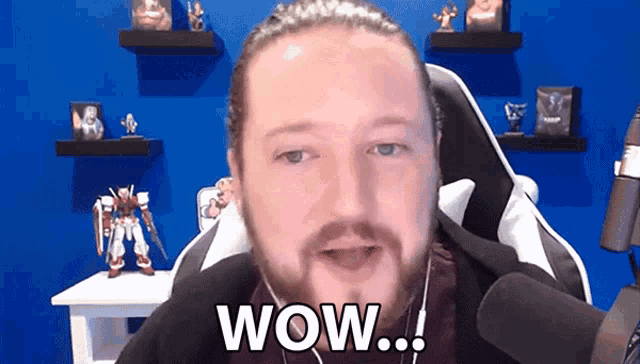 a man with a beard is sitting in front of a microphone and says wow