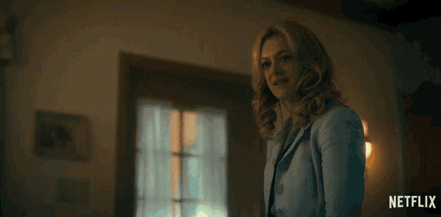 a woman in a suit stands in front of a window and the word fine is on the screen