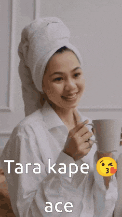 a woman with a towel wrapped around her head is holding a cup of tea