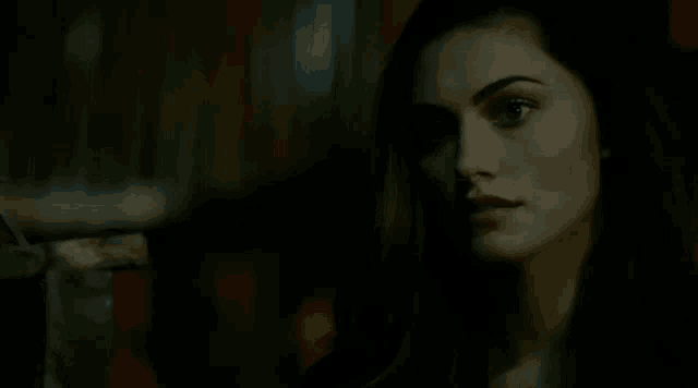 a woman is looking at the camera in a dark room .