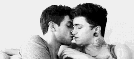 a black and white photo of two men kissing each other .