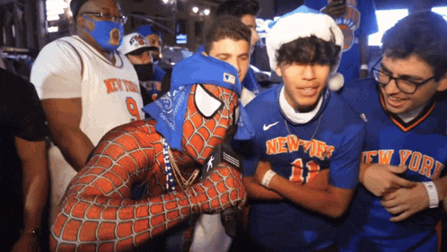 a man in a spiderman costume is surrounded by people wearing new york shirts