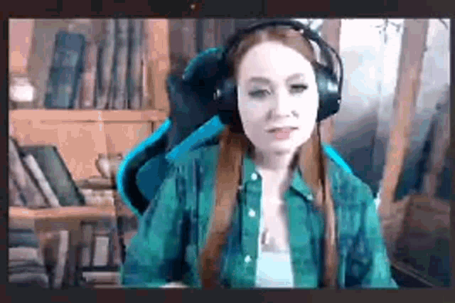 a woman wearing headphones and a green shirt is sitting in a blue chair .