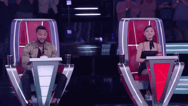 a man and a woman are sitting next to each other on a stage in front of a crowd .