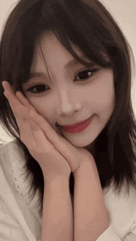 a woman with her hand on her face looks at the camera