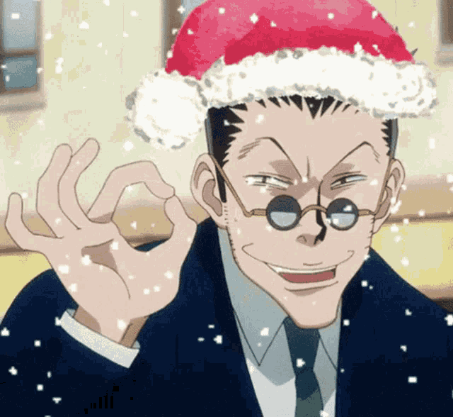 a man in a suit and tie wearing a santa hat giving an ok sign