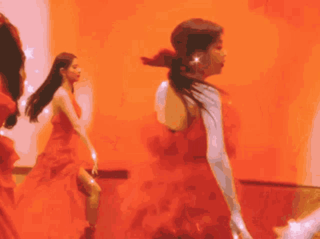 a woman in a red dress is dancing with another woman