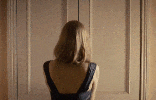 a woman in a black dress is standing in front of a white door