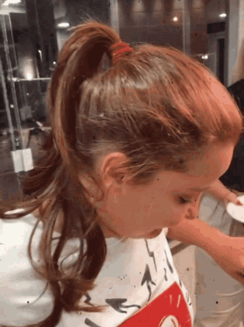 a little girl with a ponytail and a mickey mouse shirt on