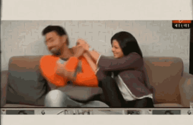 a man and a woman are sitting on a couch with their hands on each other .