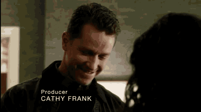 a man is smiling in front of a woman and the name cathy frank is on the screen