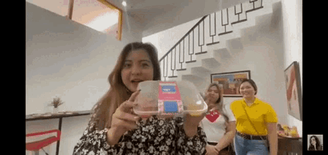 a woman is holding a container of food in front of a staircase .