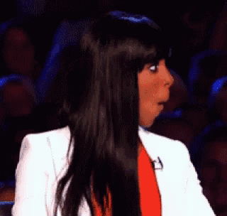 a woman with a surprised look on her face is wearing a white jacket and a red dress .