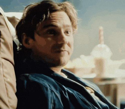 a man in a blue jacket is sitting in a chair with his head resting on his arm