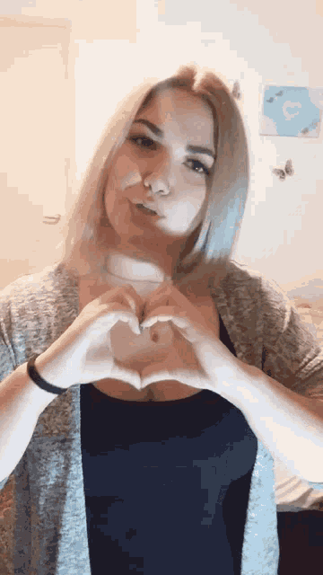 a woman is making a heart with her hands