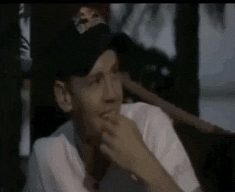 a man wearing a red bull hat and a white shirt is sitting in a chair .