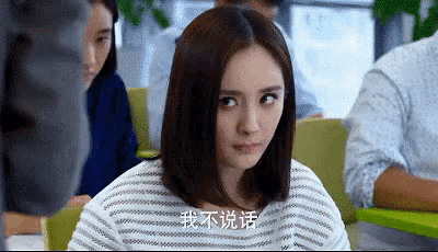 a woman in a striped shirt is sitting in a classroom with chinese writing on her shirt .