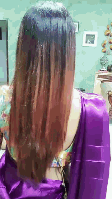 a woman with long hair is wearing a purple saree