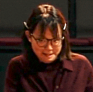 a close up of a woman wearing glasses and a burgundy shirt