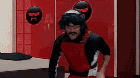 a man in a red and black costume is standing in a room with a bed .