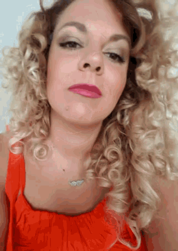 a woman with blonde curly hair wearing a red dress