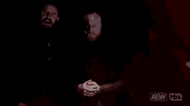 three bearded men are standing next to each other in a dark room .