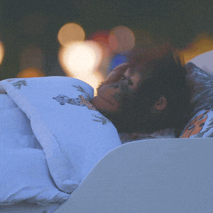 a monkey is sleeping in a bed with a blanket with a leopard print on it