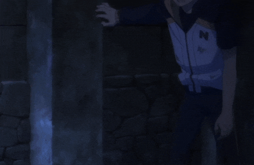 a man in a jacket with the letter n on it stands in a dark room
