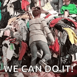a person is standing in a pile of clothes with the words `` we can do it '' written on it .