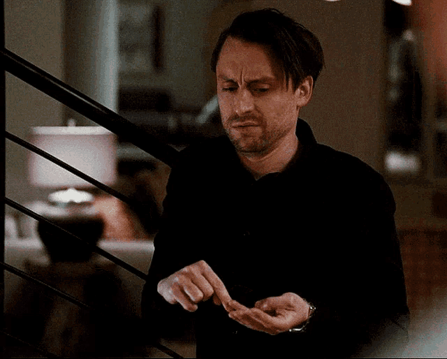 a man in a black shirt is standing in front of a lamp