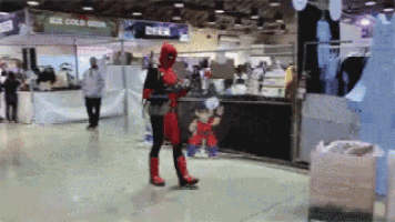a man in a deadpool costume stands in front of a ice cold drink stand