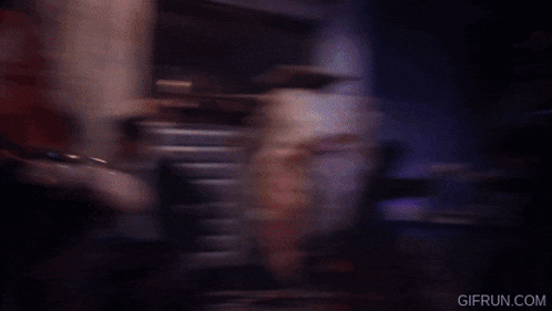 a woman wearing a red jacket and silver top is dancing in a dark street .
