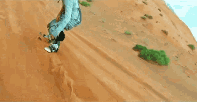 a person is riding a snowboard down a sand dune .